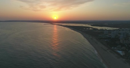 Aerial sunset view of Praia dos Tres Irmaos (Three Brothers beach) in Alvor, famous tourist destination in Western Algarve Coast, Portugal.