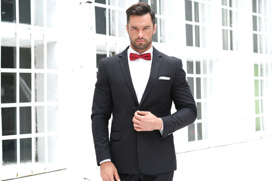 Classy look is always the best. Man wearing a black suit and red bow-tie.