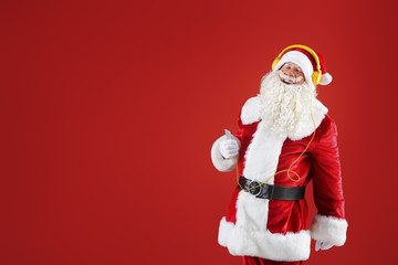 Portrait of cool Santa Claus listening to music on color background