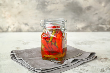 Jar with canned chili pepper on table
