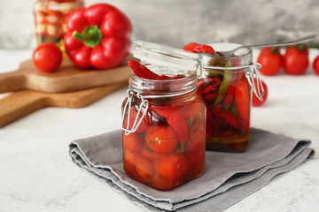 Jars with canned tomatoes and chili pepper on table