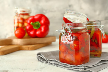 Jars with canned tomatoes and chili pepper on table