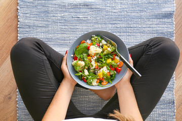 Woman holding bowl with fresh salad, top view