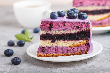 Homemade cake with souffle cream and blueberry jam with cup of coffee on a gray concrete  background. side view.