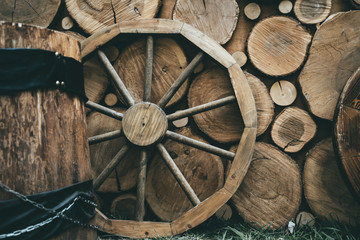 Wooden wheel on wood rustic background, vintage toned