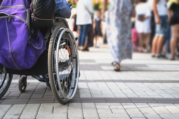 Wheelchair with disabled man on blurred background of many people on street. Problem of people with disabilities and society concept