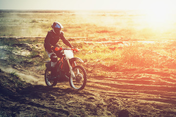 Fototapeta na wymiar Motocross rider moves fast outdoor in sunlight with copy space