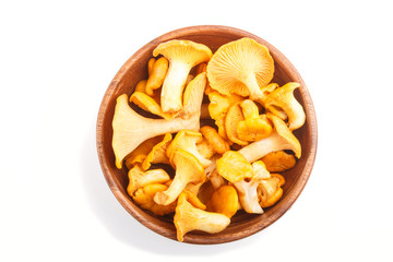Bunch of chanterelle mushrooms in wooden bowl isolated on white background.