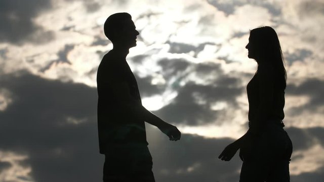 Cheery young man going and kissing his tender girlfriend at sunset in slo-mo 