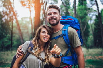 Smiling couple walking with backpacks over natural background