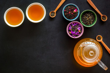 Cups, teapot, dry tea frame on black background top view mockup