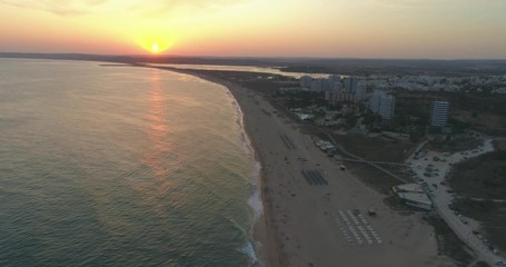 Aerial sunset view of Praia dos Tres Irmaos (Three Brothers beach) in Alvor, famous tourist destination in Western Algarve Coast, Portugal.