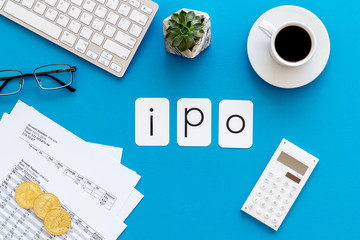 Initial Public Offering IPO with coins, calculation table, office tools, coffee on blue background...