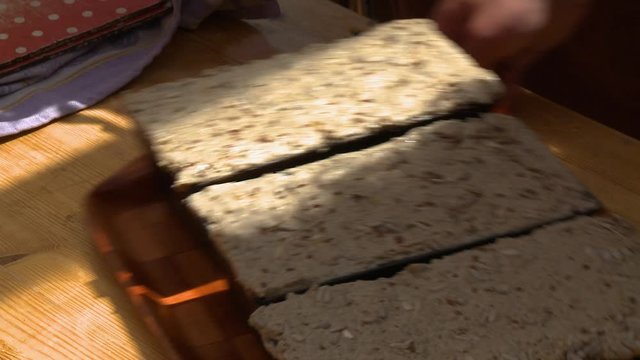 Steady, close up shot of a towel removed to reveal loaves of nut bread.