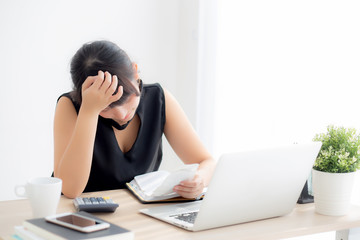 Beautiful young asian woman calculating expenses household and writing notebook on desk, girl checking bill and stress and note, female worry debt and tax, finance and business concept.