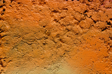 The texture of the unevenly painted wall is light orange. The wall with irregularities and dimples. The background of the orange concrete wall.