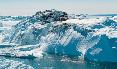 Iceberg and ice from glacier in arctic nature landscape on Greenland. Aerial photo drone photo of icebergs in Ilulissat icefjord. Affected by climate change and global warming. - obrazy, fototapety, plakaty