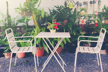 White tables and chairs with flower vases in the garden and warm light.