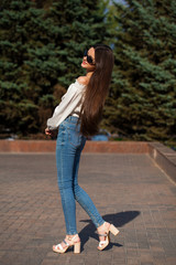 Pretty stylish brunette girl in blue jeans and white blouse