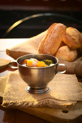 Fresh vegetarian soup made of broccoli, squash, onion, carrot, potato and tomato, photographed with natural light (Selective Focus, Focus on the squash pieces in the middle of the soup)