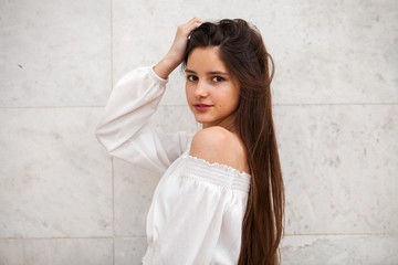 Young beautiful girl on a background of a white marble wall