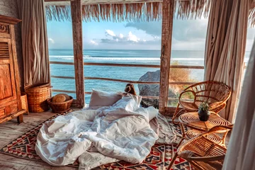 Fotobehang Vrouw geniet van ochtendvakanties op tropische strandbungalow met uitzicht op de oceaan Ontspannende vakantie in Uluwatu Bali, Indonesië © Nichapa