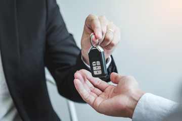 Sale agent giving Car key to customer and sign agreement contract, Insurance car concept.