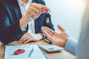 Sale agent giving Car key to customer and sign agreement contract, Insurance car concept.