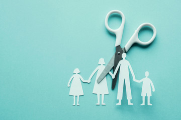 White scissor cutting family paper cut out on blue background, causes and effects on child...