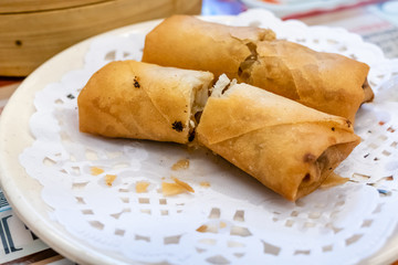 Spring rolls in a plate in front of bamboo steamers