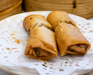 Spring rolls in a plate in front of bamboo steamers