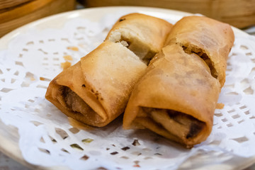 Spring rolls in a plate in front of bamboo steamers