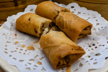 Spring rolls in a plate in front of bamboo steamers