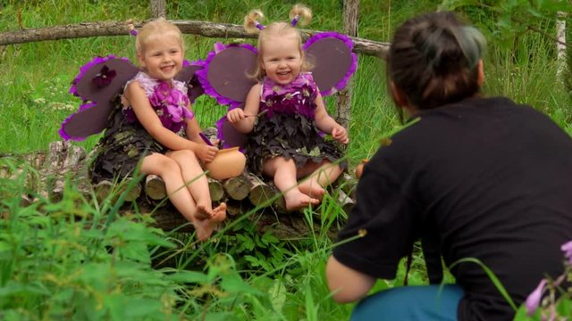 Photographer takes pictures of girls playing butterflies. Girls wear butterfly wings