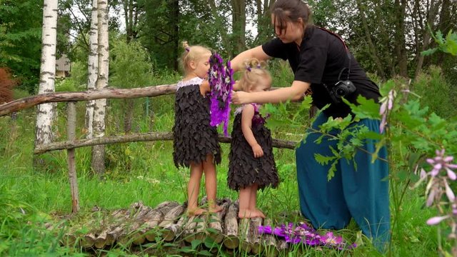 Photographer helps girl to put on butterfly wings. Preparing for a thematic fairy photo shoot