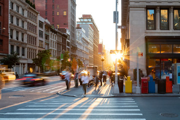 Man walking through the crosswalk at the busy intersection of 5th Avenue and 23rd Street in New York City with sunset background