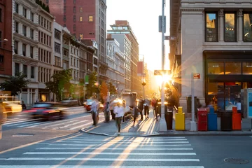 Poster Man loopt door het zebrapad op het drukke kruispunt van 5th Avenue en 23rd Street in New York City met zonsondergang op de achtergrond © deberarr