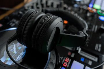 Obraz na płótnie Canvas Professional dj headphones on audio mixer controller.Big black headset on sound mixing panel.Audio equipment for disc jockey