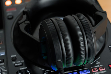 Fototapeta na wymiar Professional dj headphones on audio mixer controller.Big black headset on sound mixing panel.Audio equipment for disc jockey