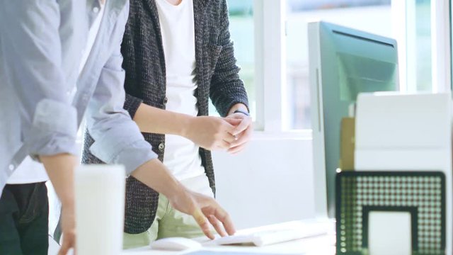 two asian businessmen discussing business in front of desktop computer