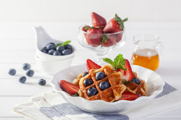 Strawberry waffles and blueberries with honey for breakfast