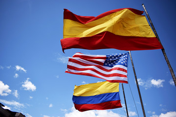 Bamderas de Colombia, Estados Unidos y España juntas en un dia con mucho sol y viento.