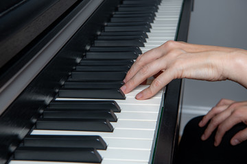 Close up of a woman playing the piano. Left hand only plays a melody, one note at a time.