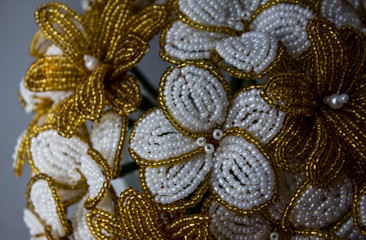 Bouquet of beaded flowers, white and gold flowers. Macro view from the side.