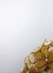 Golden bouquet with white flowers from beads on a gray background. Flowers at the bottom of the background.
