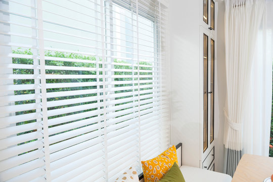 Close up view of window with horizontal blinds. White Roller Blinds or Louver curtains at the glass window