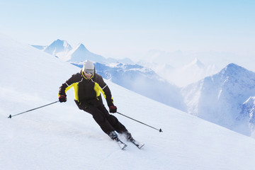 Alpine skier on piste running downhill