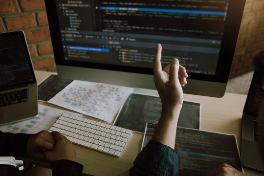 Two software developers are analyzing together about the code written into the program on the computer.