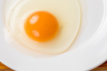 白いお皿に生卵が乗っているコピースペース、朝食、料理用