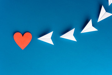 Focus, assertiveness, work yourself concept. Paper heart shape with airplane on blue background - obrazy, fototapety, plakaty